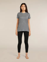 A woman stands barefoot against a plain beige studio background, wearing a heather gray short-sleeve crewneck top and black leggings. - Icebreaker Merino 260 Fastray 25" High Rise Tights (Women's) - Black