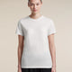 A woman modeling a plain white short-sleeve crewneck t-shirt against a solid beige background. - Icebreaker Merino 150 Tech Lite Short Sleeve T-Shirt (Women's) - Ecru Heather