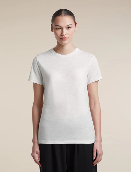 A woman modeling a plain white short-sleeve crewneck t-shirt against a solid beige background. - Icebreaker Merino 150 Tech Lite Short Sleeve T-Shirt (Women's) - Ecru Heather