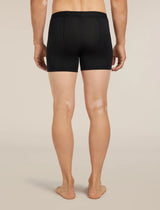 Rear view of a person wearing black men's boxer briefs against a plain light beige studio background. - Icebreaker Merino Blend 125 Cool-Lite Anatomica Boxers (Men's) - Black