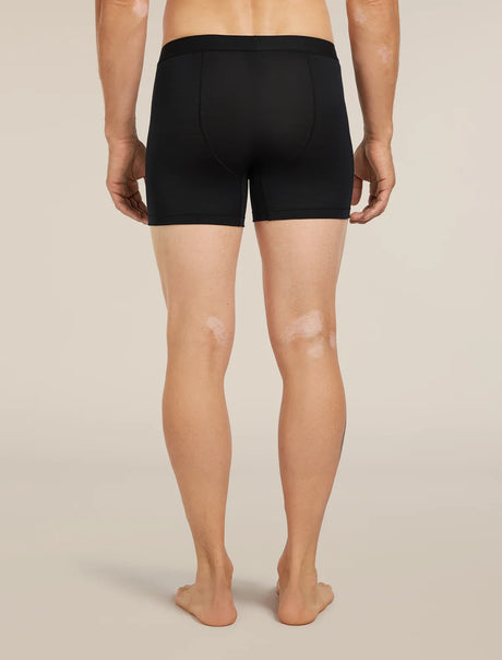 Rear view of a person wearing black men's boxer briefs against a plain light beige studio background. - Icebreaker Merino Blend 125 Cool-Lite Anatomica Boxers (Men's) - Black