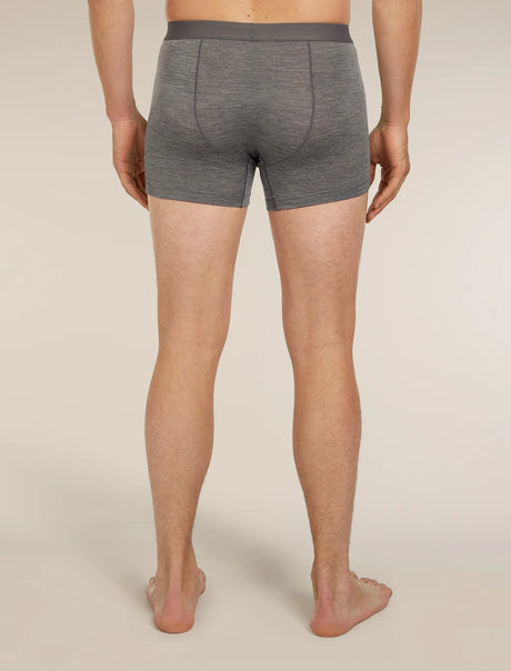 A man viewed from the back wearing heather gray boxer briefs, standing barefoot against a plain light beige studio background. - Icebreaker Merino Blend 125 Cool-Lite Anatomica Boxers (Men's) - Gritstone Heather