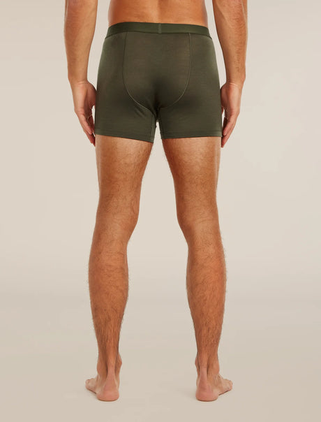A man viewed from the back wearing olive green boxer briefs, standing barefoot against a plain light beige studio background. - Icebreaker Merino Blend 125 Cool-Lite Anatomica Boxers (Men's) - Dark Loden