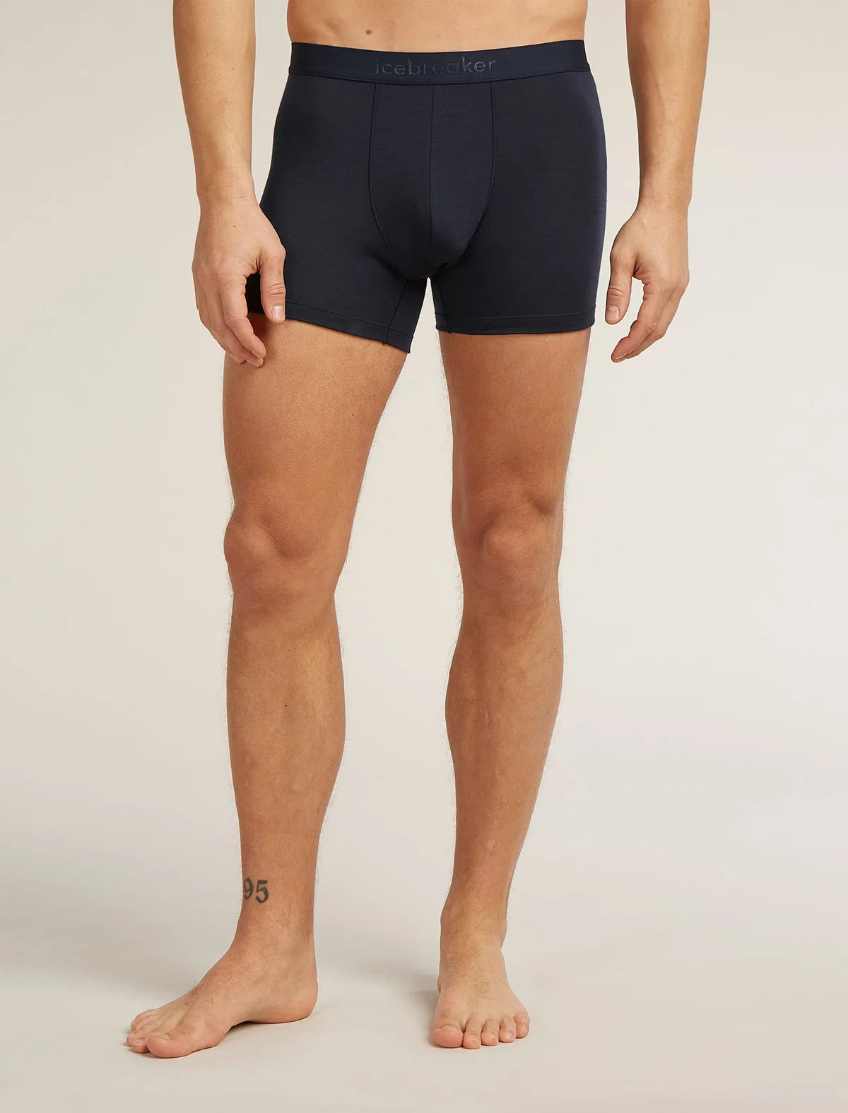 A man wearing dark navy blue boxer briefs, shown from the waist down against a light beige studio background. The brand name 'celery' is subtly printed on the front waistband. - Icebreaker Merino Blend 125 Cool-Lite Anatomica Boxers (Men's) - Midnight Navy