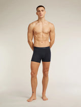 A shirtless male model stands against a light gray studio background wearing dark navy boxer briefs. - Icebreaker Merino Blend 125 Cool-Lite Anatomica Boxers (Men's) - Midnight Navy