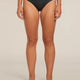 A model wearing black underwear from the waist down, standing against a neutral beige studio background. The brand name 'krelvaker' is visible on the waistband. - Icebreaker Merino Blend 125 Cool-Lite Sprite Hipster (Women's) - Black