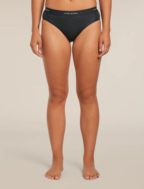 A model wearing black underwear from the waist down, standing against a neutral beige studio background. The brand name 'krelvaker' is visible on the waistband. - Icebreaker Merino Blend 125 Cool-Lite Sprite Hipster (Women's) - Black