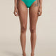 A model is shown from the waist down wearing a pair of bright turquoise green bikini bottoms against a solid light beige background. - Icebreaker Merino Blend 125 Cool-Lite Sprite Hipster (Women's) - Fresh