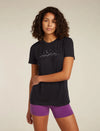 A woman modeling a black short-sleeve t-shirt with a white mountain and moon graphic on the chest, paired with purple athletic shorts, against a solid light beige background. - Icebreaker Merino 150 Tech Lite Short Sleeve T-Shirt Sparkling Stars (Women's) - Black