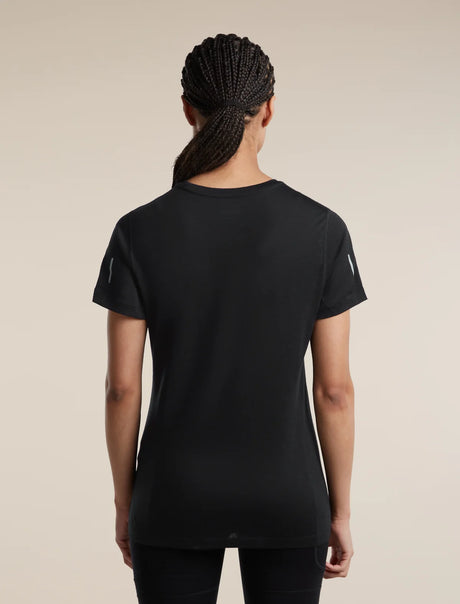 Rear view of a woman wearing a black short-sleeve athletic T-shirt with subtle reflective details on the sleeves, set against a solid beige background. - Icebreaker Merino Blend 125 Cool-Lite Speed Short Sleeve T-Shirt (Women's) - Black