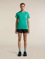 A woman stands facing forward in a studio wearing a bright green athletic short-sleeve T-shirt, black running shorts, black shoes, and bright green socks against a plain warm beige background. - Icebreaker Merino Blend 125 Cool-Lite Speed Short Sleeve T-Shirt (Women's) - Fresh