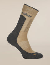A single mid-calf athletic sock shown on a ghost mannequin against a solid light beige background. The sock features a beige knit body with a dark gray heel, toe, and ribbed cuff, and has the brand name 'saker' printed in dark gray on the upper calf. - Icebreaker Merino Hike+ Medium Crew Socks (Men's) - Cumin/Obsidian