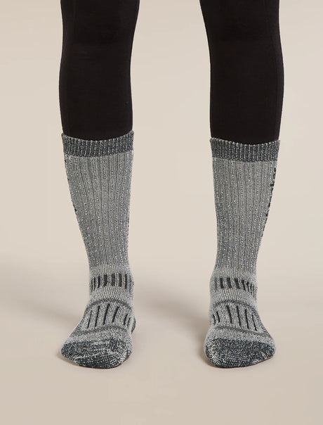 Gray socks with black patterns worn with black leggings on a beige background - Icebreaker Merino Hike+ Mountaineer Mid Calf Socks (Women's) - Jet Heather/Black