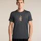 A man wearing a dark gray heathered t-shirt with a small graphic of a bear carrying a ski pole on the chest, standing against a solid beige background. - Icebreaker Merino 150 Tech Lite Short Sleeve T-Shirt Bear Tour (Men's) - Obsidian
