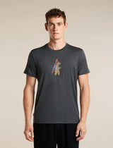 A man wearing a dark gray heathered t-shirt with a small graphic of a bear carrying a ski pole on the chest, standing against a solid beige background. - Icebreaker Merino 150 Tech Lite Short Sleeve T-Shirt Bear Tour (Men's) - Obsidian