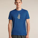 A man wearing a royal blue crewneck t-shirt with a distressed white graphic of a bear carrying a ski pole, paired with dark gray athletic pants, against a solid beige studio background. - Icebreaker Merino 150 Tech Lite Short Sleeve T-Shirt Bear Tour (Men's) - Lazurite