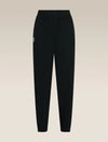 Black jogger-style pants with an elastic waistband and a small white embroidered logo on the left hip, shown against a light beige gradient background. - Icebreaker Merino Blend 150 Drift Pants (Women's) - Black
