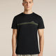 A man wearing a black short-sleeve crewneck t-shirt with a green and yellow mountain graphic across the chest, paired with light gray trousers, set against a plain beige studio background. - Icebreaker Merino 150 Tech Lite Short Sleeve T-Shirt Range Stripes (Men's) - Black