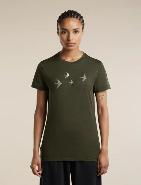 A woman modeling an olive green short-sleeve t-shirt with a graphic of four flying birds in light gray on the chest, set against a plain beige background. - Icebreaker Merino 150 Tech Lite Short Sleeve T-Shirt Bird Transit (Women's) - Dark Loden