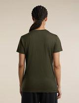 A woman viewed from the back wearing a short-sleeve crew-neck t-shirt in olive green, paired with dark pants, against a solid light beige background. - Icebreaker Merino 150 Tech Lite Short Sleeve T-Shirt Bird Transit (Women's) - Dark Loden