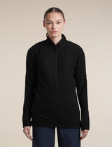 A woman modeling a black long-sleeve quarter-zip athletic pullover against a solid beige studio background. - Icebreaker Merino 400 RealFleece Grid Peaksland Long Sleeve Half Zip (Women's) - Black