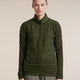 A model wearing an olive green waffle-knit quarter-zip pullover sweater and olive pants, standing against a solid beige background. - Icebreaker Merino 400 RealFleece Grid Peaksland Long Sleeve Half Zip (Women's) - Dark Loden