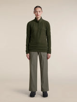 A model stands facing forward wearing an olive green quarter-zip long-sleeve top and matching olive green wide-leg pants against a plain beige studio background. - Icebreaker Merino 400 RealFleece Grid Peaksland Long Sleeve Half Zip (Women's) - Dark Loden