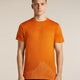 A man wearing a bright orange athletic t-shirt with a subtle white low-poly mountain graphic near the hem, standing against a neutral beige background. - Icebreaker Merino 150 Tech Lite Short Sleeve T-Shirt 3D Mapping (Men's) - Spice