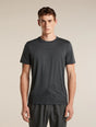 A man wearing a dark gray short-sleeve athletic t-shirt with a subtle mountain line-art graphic near the hem, paired with dark gray athletic pants, against a solid beige background. - Icebreaker Merino 150 Tech Lite Short Sleeve T-Shirt 3D Mapping (Men's) - Obsidian