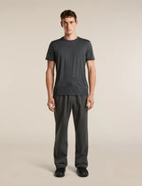 A man modeling a dark gray short-sleeve athletic t-shirt and matching dark gray pants against a solid light beige background. - Icebreaker Merino 150 Tech Lite Short Sleeve T-Shirt 3D Mapping (Men's) - Obsidian