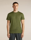 A man wearing an olive green athletic t-shirt with a subtle mountain line-art graphic near the hem, paired with dark gray athletic pants, standing against a solid beige background. - Icebreaker Merino 150 Tech Lite Short Sleeve T-Shirt 3D Mapping (Men's) - Sphagnum