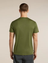 A man viewed from the back wearing a short-sleeve crew-neck t-shirt in olive green, paired with dark gray pants, against a plain beige studio background. - Icebreaker Merino 150 Tech Lite Short Sleeve T-Shirt 3D Mapping (Men's) - Sphagnum