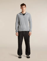 A man modeling a light gray full-zip hooded athletic jacket over a black shirt and black pants, standing against a plain beige studio background. - Icebreaker 150 MerinoFine Ace Long Sleeve Zip Hoodie (Men's) - Proto Grey