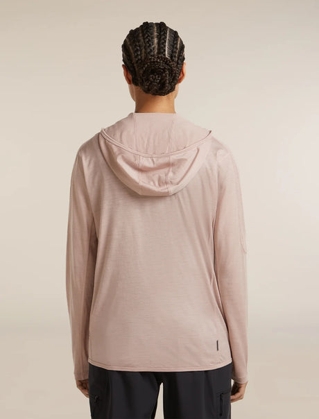 A person shown from the back wearing a light blush pink hooded long-sleeve athletic top and dark pants, photographed against a plain warm off-white studio background. - Icebreaker 150 MerinoFine Ace Long Sleeve Zip Hoodie (Women's) - Pink Quartz