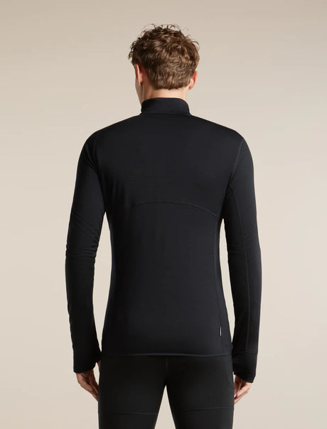 A man viewed from the back wearing a black long-sleeve athletic half-zip top and matching black pants against a plain beige studio background. - Icebreaker Merino Blend 200 RealFleece Descender Long Sleeve Half Zip (Men's) - Black