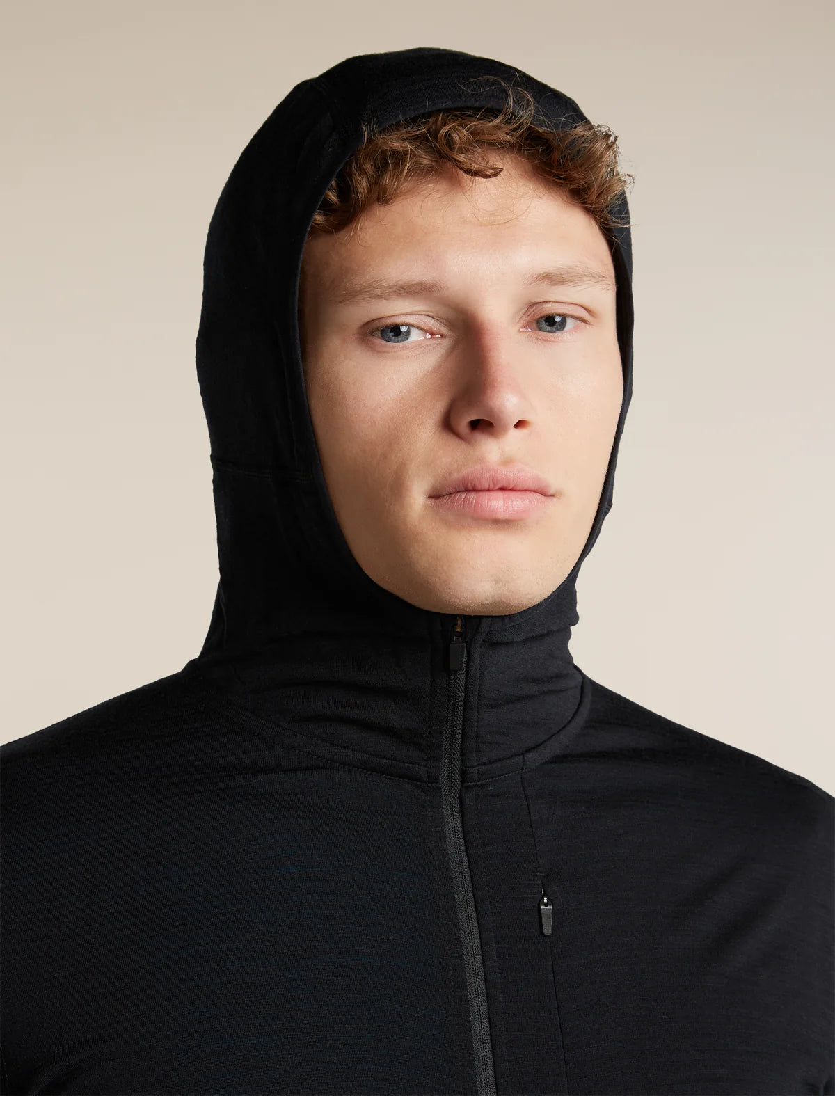 A close-up shot of a man wearing a black hooded zip-up jacket against a solid beige background. - Icebreaker Merino Blend 200 RealFleece Descender Long Sleeve Zip Hoodie (Men's) - Black