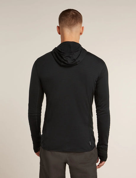 A man viewed from behind wearing a black long-sleeve hooded athletic top and dark gray pants, standing against a plain light beige studio background. - Icebreaker Merino Blend 300 RealFleece™ Descender Long Sleeve Zip Hoodie (Men's) - Black