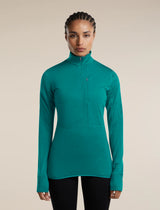 A woman modeling a teal green long-sleeve half-zip athletic top against a solid beige background. - Icebreaker Merino Blend 200 RealFleece Descender Long Sleeve Half Zip (Women's) - Tidal Teal