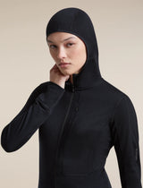 A woman wearing a black hooded athletic jacket with a full front zipper, photographed against a plain warm beige studio background. - Icebreaker Merino Blend 200 RealFleece Descender Long Sleeve Zip Hoodie (Women's) - Black