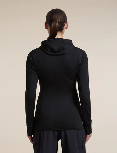Rear view of a woman wearing a black long-sleeve hooded athletic top and dark pants against a plain beige studio background. - Icebreaker Merino Blend 200 RealFleece Descender Long Sleeve Zip Hoodie (Women's) - Black