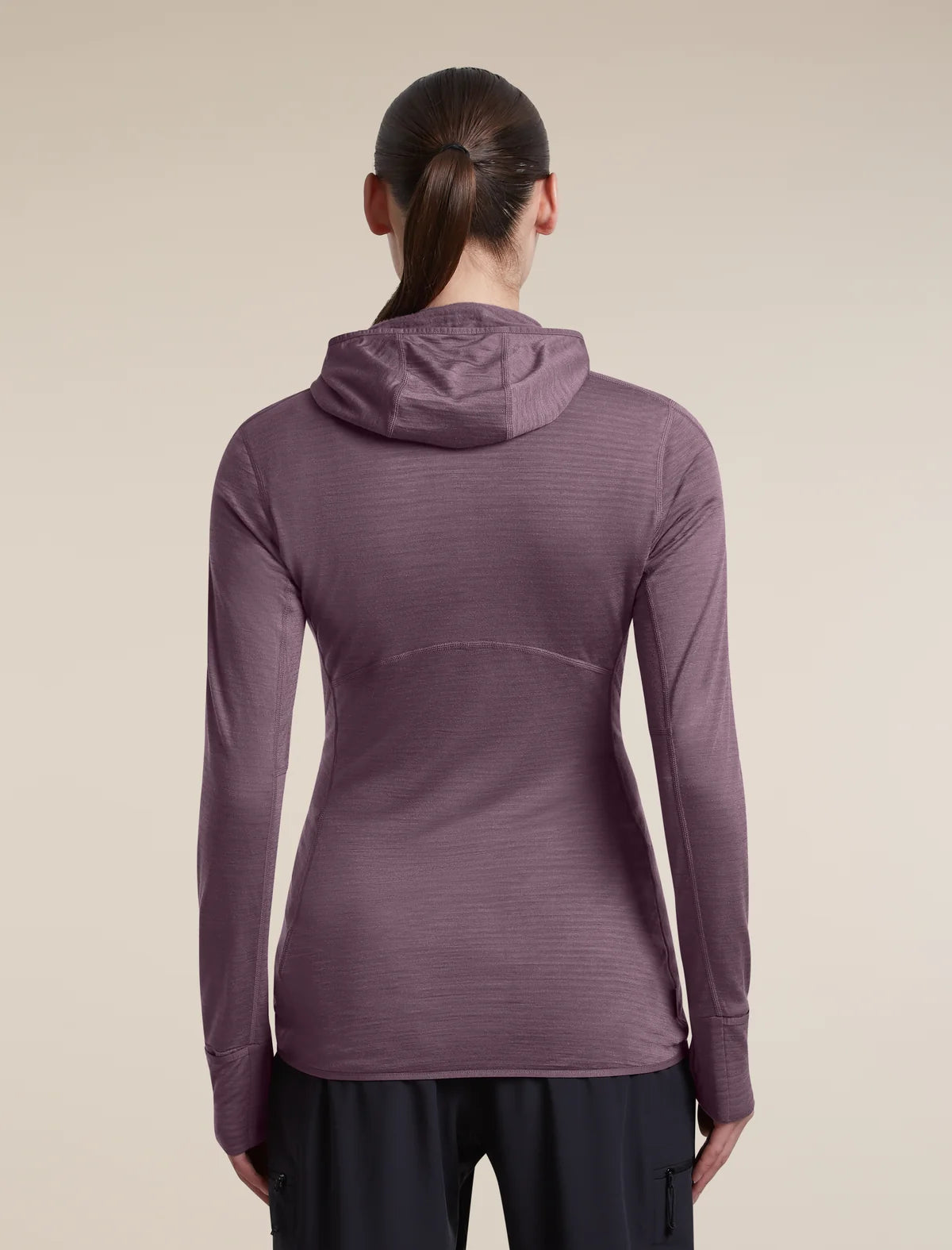 A woman viewed from the back wearing a long-sleeve hooded athletic top in a muted mauve-purple color, paired with dark pants, against a plain beige studio background. - Icebreaker Merino Blend 200 RealFleece Descender Long Sleeve Zip Hoodie (Women's) - Grey Plum - Purple