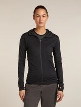 A woman modeling a black full-zip hooded athletic jacket over a dark gray shirt, paired with gray pants, against a plain light beige studio background. - Icebreaker Merino Blend 300 RealFleece Descender Long Sleeve Zip Hoodie (Women's) - Black