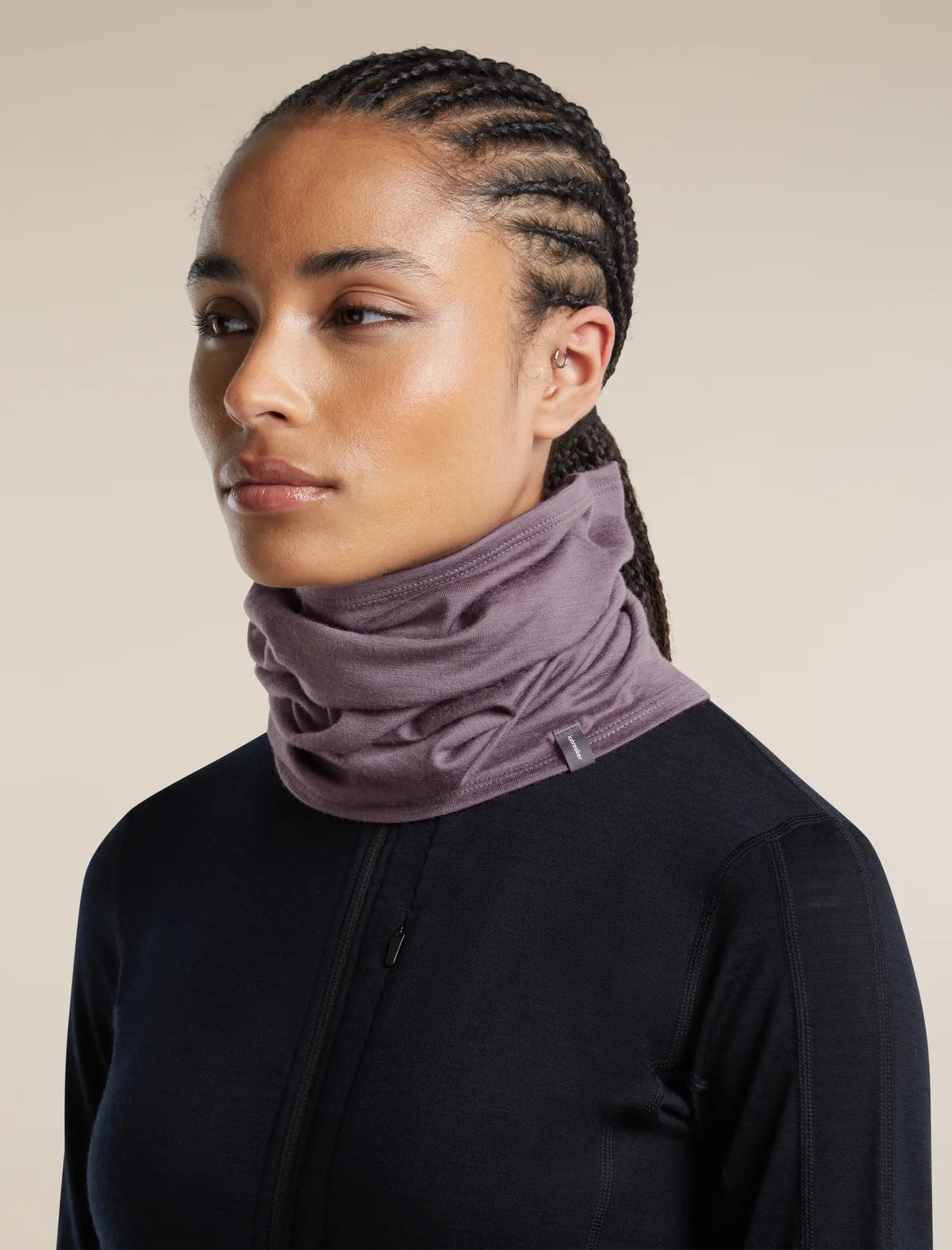 A woman wearing a dusty mauve-purple athletic neck gaiter and a black zip-up jacket, photographed against a solid light beige background. - Icebreaker Merino 200 Flexi Chute (Unisex) - Grey Plum