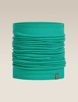 A teal green tubular neck gaiter or face mask, folded to show its layered fabric texture, with a small dark brand tag on the bottom right, set against a solid beige background. - Icebreaker Merino 200 Flexi Chute (Unisex) - Fresh