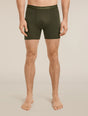 A man modeling dark olive green men's boxer briefs with a matching elastic waistband featuring the 'icebreaker' brand name, shown against a solid light beige background. - Icebreaker Merino 150 Anatomica Boxers (Men's) - Dark Loden