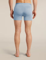 Rear view of a model wearing light blue athletic compression shorts against a warm beige studio background. - Icebreaker Merino 150 Anatomica Boxers (Men's) - Zinc Blue