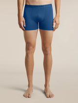 A model from the waist down wearing blue Lebrecker men's boxer briefs, standing against a solid beige studio background. - Icebreaker Merino 150 Anatomica Boxers (Men's) - Lazurite