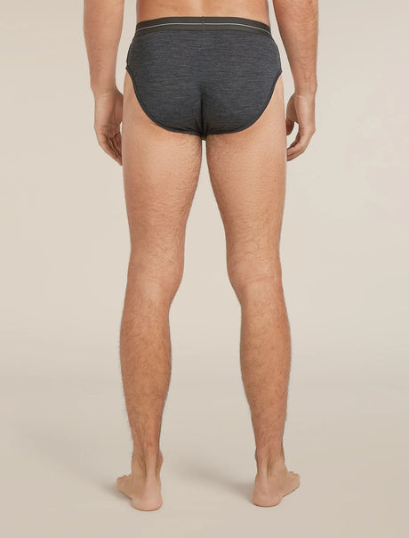 Rear view of a man wearing dark gray heathered briefs against a light beige studio background. - Icebreaker Merino 150 Anatomica Briefs (Men's) - Jet Heather