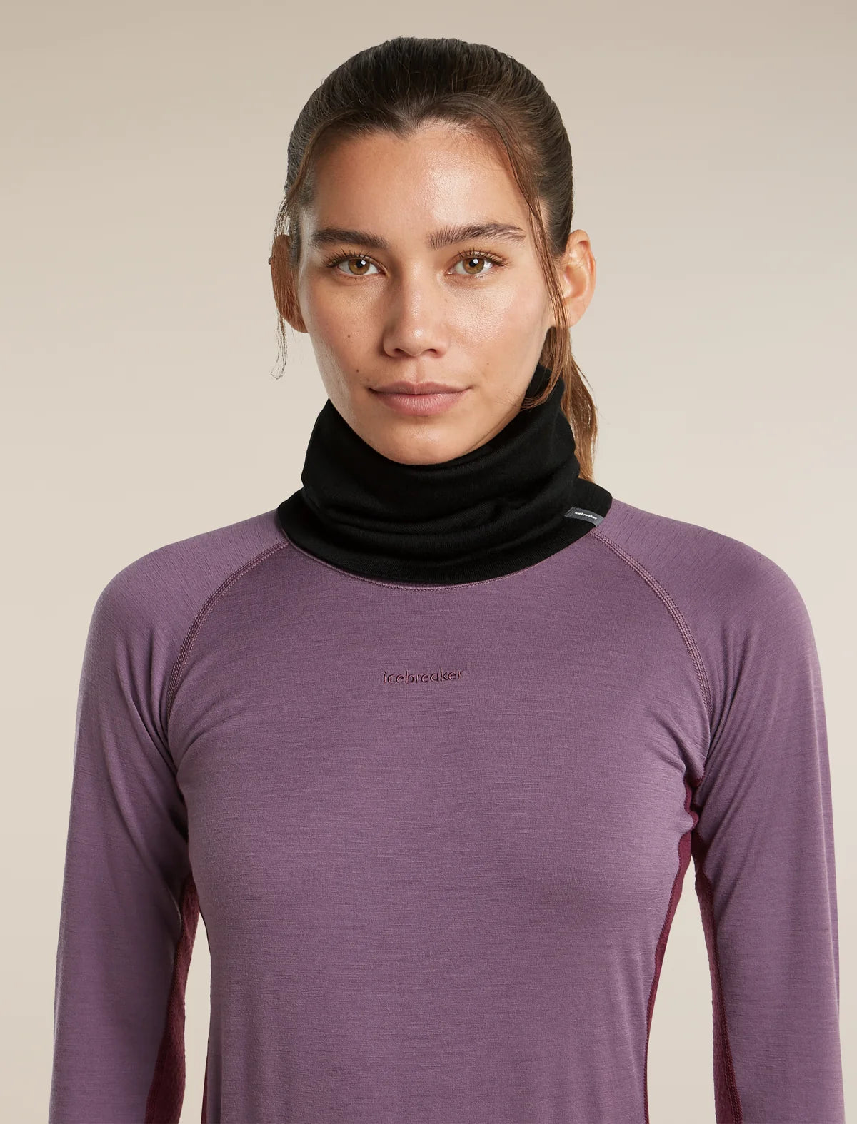 A woman wearing a purple long-sleeve athletic top with a black neck gaiter, photographed against a plain beige studio background. - Icebreaker Merino 260 Apex Chute (Unisex) - Black