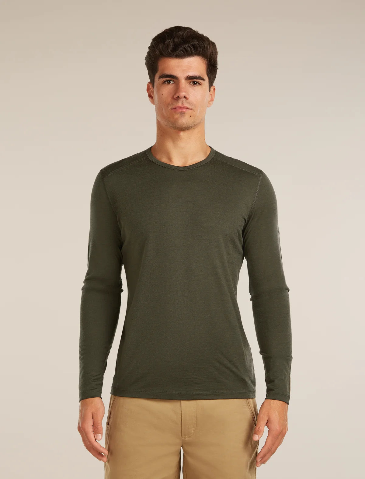 Man wearing a green long-sleeve shirt against a beige background - Icebreaker Merino 200 Oasis Long Sleeve Crew Thermal Top (Men's) - Dark Loden